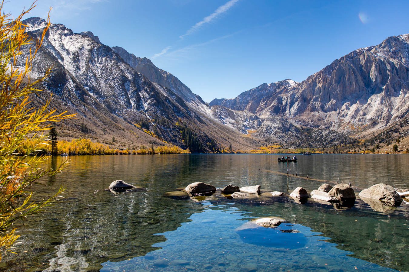 Clear reflections of Sierra Nevada mountains and autumn aspens on Convict Lake with golden leaves in the foreground, Mammoth Lakes, California fall colors.